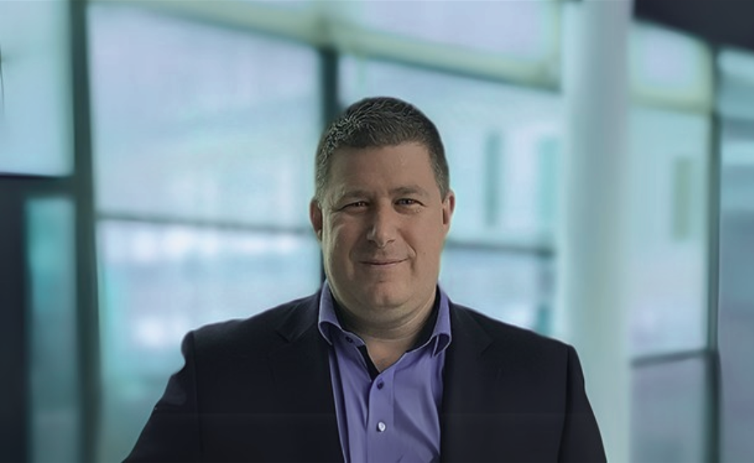 Portrait of a business executive in a suit standing in front of a bright office background – representing key business and technology trends expected this year.