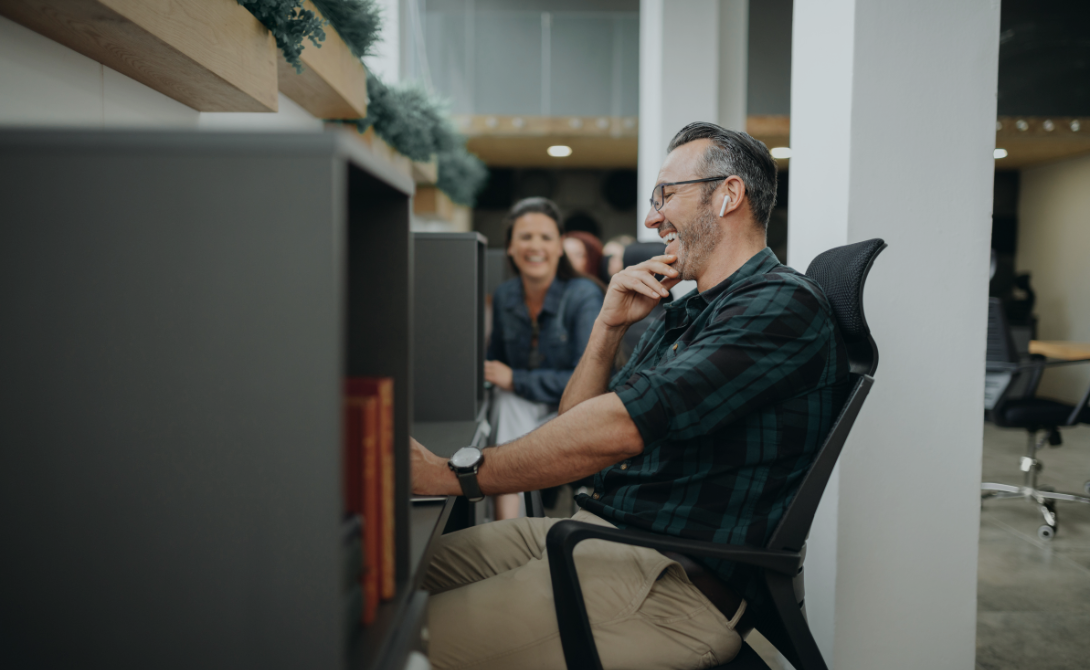 Smiling employee interacting with a digital interface at the office – representing how users benefit from modern digital platforms in the workplace.