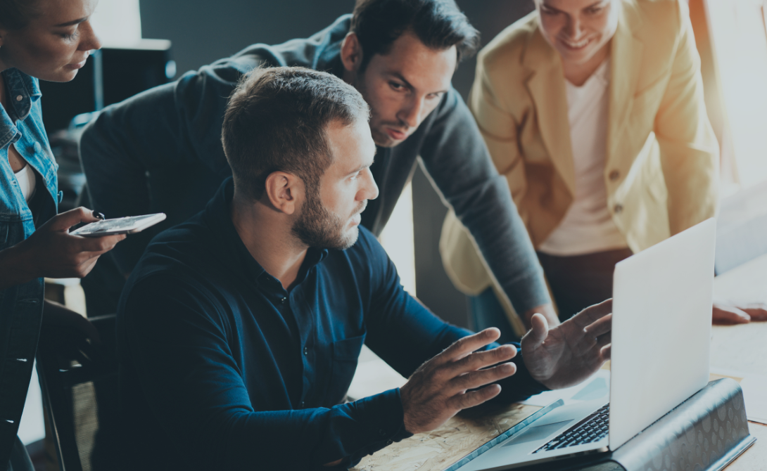 Team of IT professionals discussing in front of a laptop – modern IT infrastructure for digital workplaces.