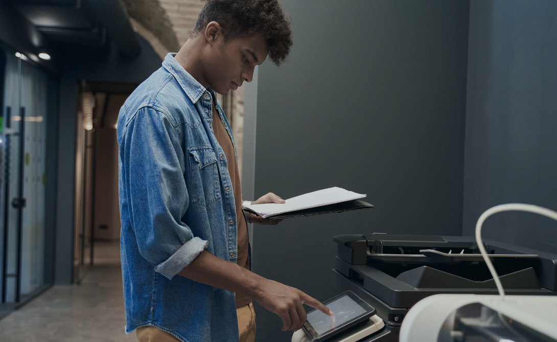 Man scanning documents using a touchscreen printer in a modern office – document digitalization with CONVOTIS
