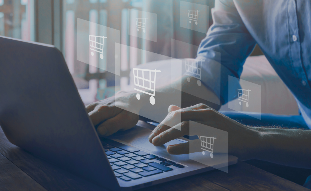 Hands typing on a laptop, overlaid with digital shopping cart icons - a symbolic image for networked omnichannel commerce.
