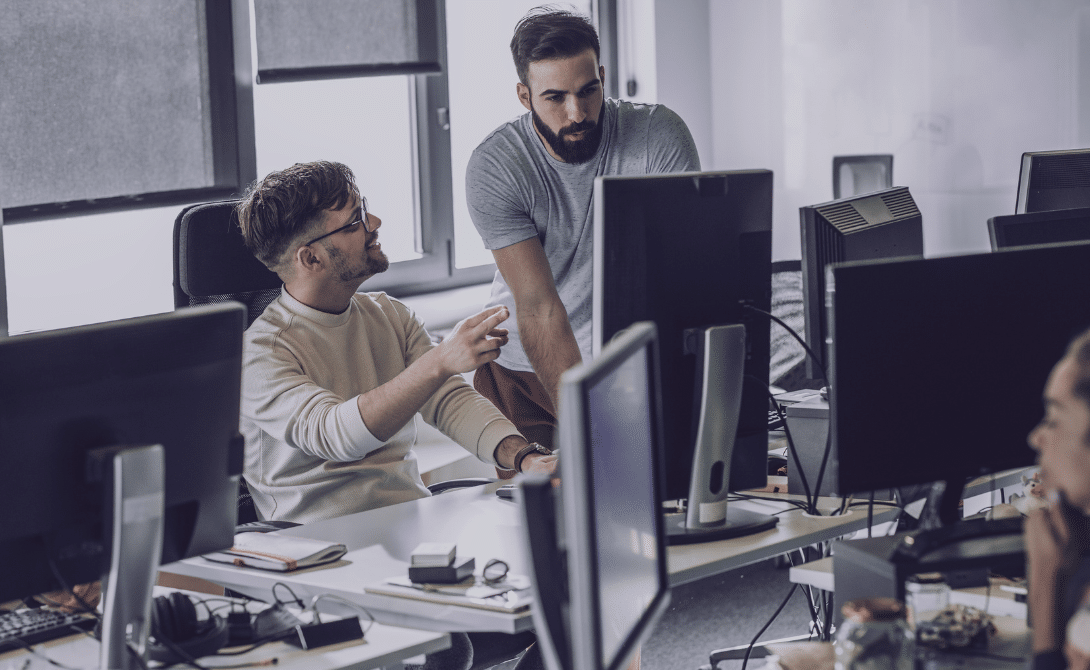 IT team discussing Cloud Automation workflows at modern workstations – representing automated infrastructure management, platform orchestration and policy-driven cloud operations.