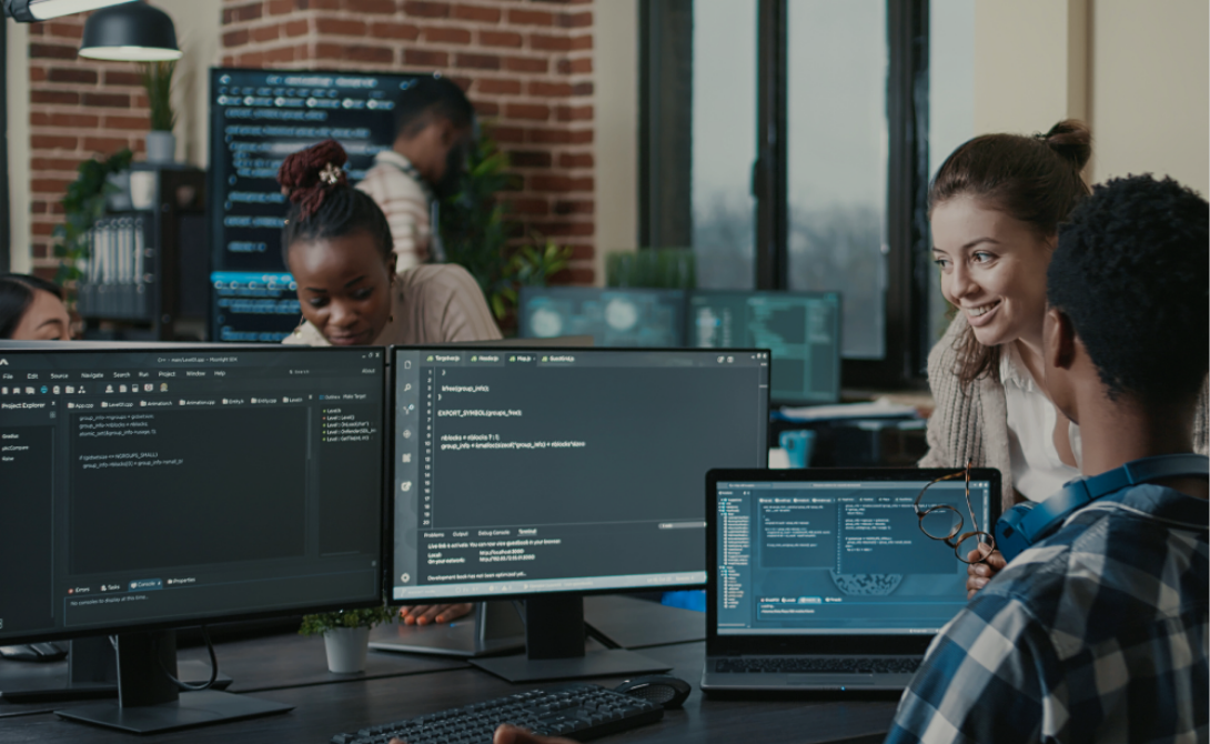 Team working on machine learning pipelines and MLOps setup on multiple computer screens in a modern office environment.