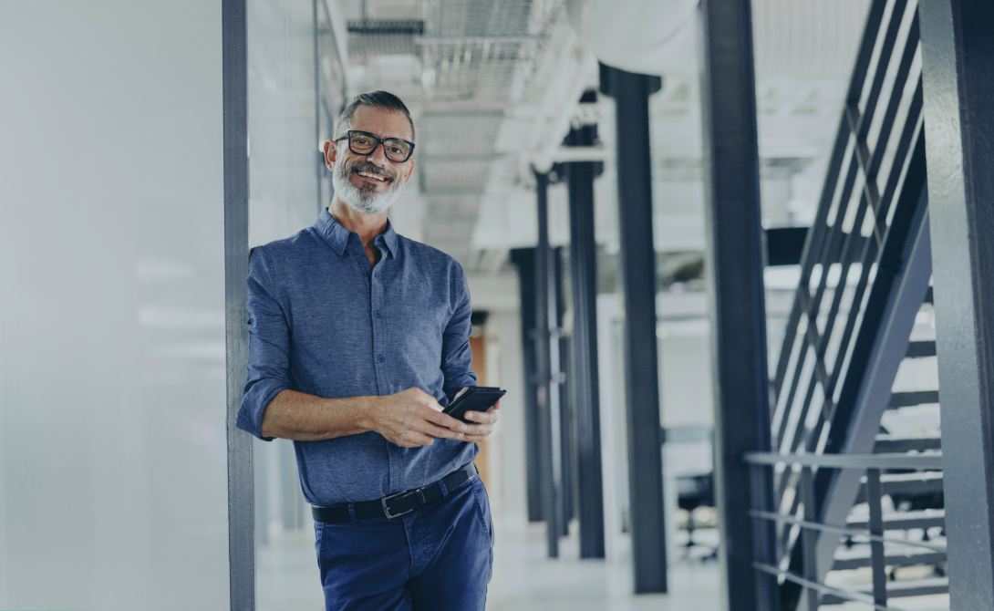 Businessman holding a smartphone in a modern office – HR digitalization with CONVOTIS.
