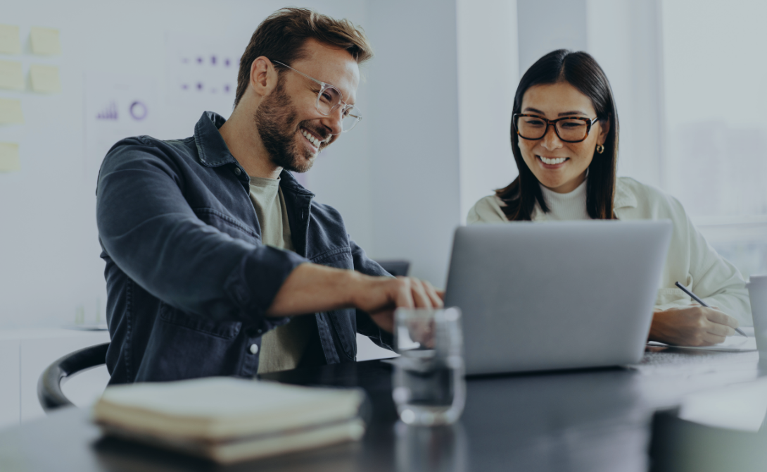 Two colleagues collaborating in front of a laptop – representing the evaluation of integrated versus best-of-breed HR software solutions.