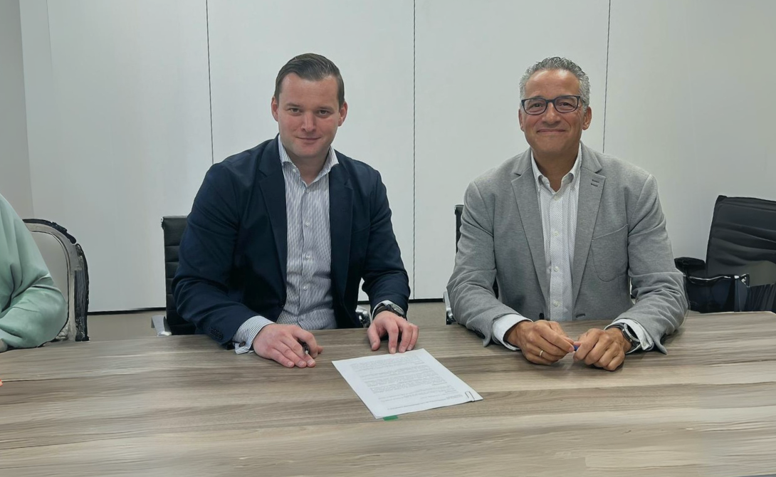 Two business professionals seated at a table with a signed agreement – symbolizing the integration of Teralco and DevCenter into the CONVOTIS Group.