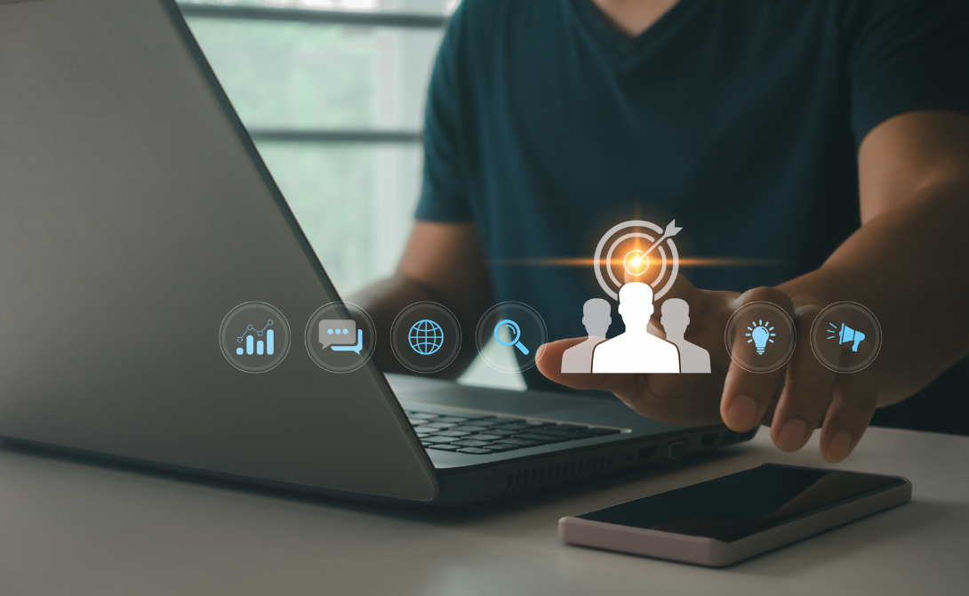 Person working on a laptop with customer targeting icons floating above – representing the role of IT in optimizing the e-commerce customer journey.