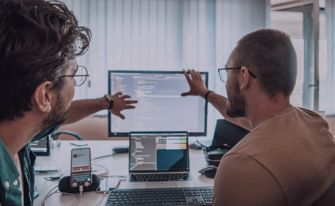 Two IT professionals discussing modular system design and scalable Software Architecture in a modern workspace – representing API-first integration and layered application structures.