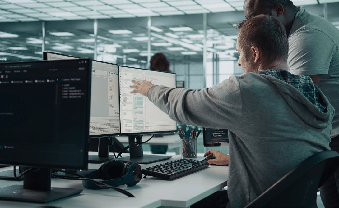 Two IT professionals configuring workflow automation on multiple screens – implementing digital process automation, RPA integration and scalable end-to-end workflows in a modern system environment.