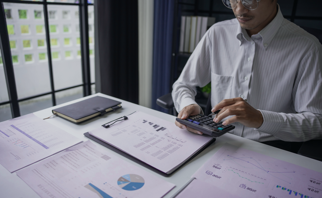 Cloud cost manager reviewing budgets and workloads using calculator and reports.